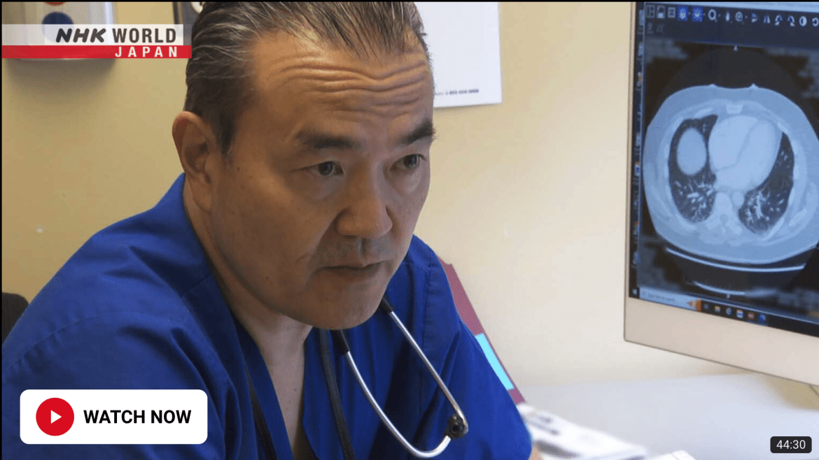Dr Yasufuku sitting in front of a computer screen showing an x-ray of a chest.